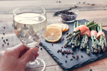 white wine in hand and bunches of asparagus wrapped in salmon