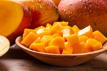 Mango fruit and mango cubes on the wooden table.