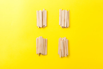 Few heap of many wooden ice cream sticks on yellow background. Concept gray crowd  and individual