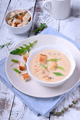 Cream soup with croutons, green onion and cheese in a white bowl