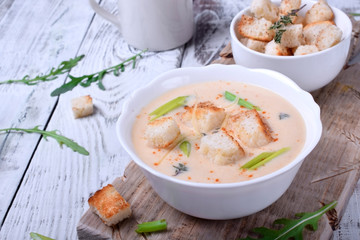 Cream soup with croutons, green onion and cheese in a white bowl