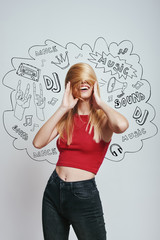 Playful mood. Cheerful young woman in red tank top covering face with her hair while standing against grey background with music theme doodles.