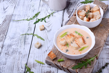 Cream soup with croutons, green onion and cheese in a white bowl
