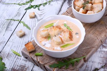 Cream soup with croutons, green onion and cheese in a white bowl