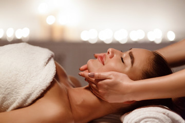 Obraz na płótnie Canvas Woman enjoying anti aging facial massage, side view