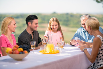 Family playing cards outdoors.