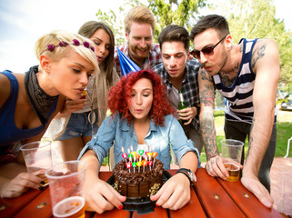 Delighted birthday girl blowing candles on birthday cake