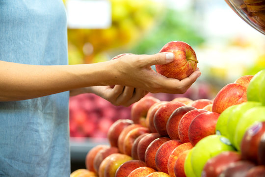 Woman's hand choosing red apple in supermarket