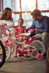 Happy family shopping new bicycle for little child in bike shop.