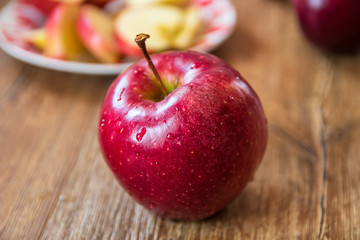Fresh organic big red apples whole and sliced on wooden table