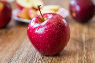Fresh organic big red apples whole and sliced on wooden table
