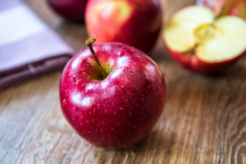 Fresh organic big red apples whole and sliced on wooden table