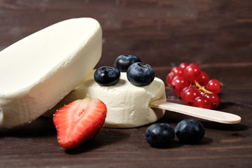 white cream ice cream on a stick with strawberries, blueberries and red currants on the dack wood background