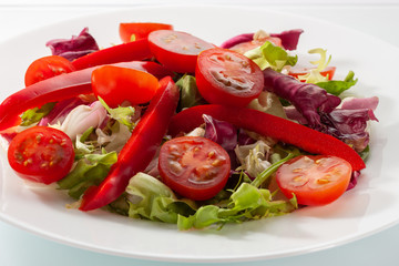 Salad with fresh vegetables on a white table