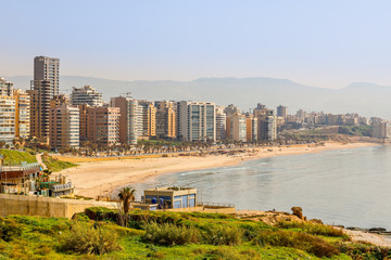 Downtown buildings and towers with road, sandy beach and sea in the foreground, Beirut, Lebanon