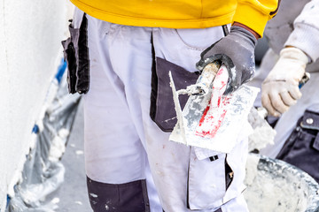 Construction worker plastering and smoothing concrete wall with cement