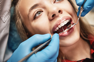 We can help you be at your best. Teen at the dental office. Dentist examining girl's teeth in...