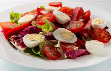Salad with fresh vegetables on a white table