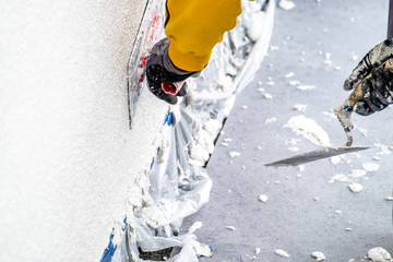 Construction worker plastering and smoothing concrete wall with cement