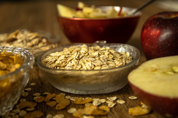 Close up photo of a cereal grain product. Barley flake from whole grain for barley porridge, fresh organic red apple, muesli and corn flakes.