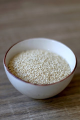 Small bowl of sesame on a wooden table. Selective focus.