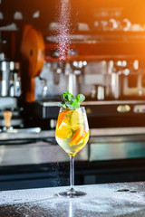 Closeup glass of white sparkling wine sangria decorated with citrus slices at bright bar counter background.