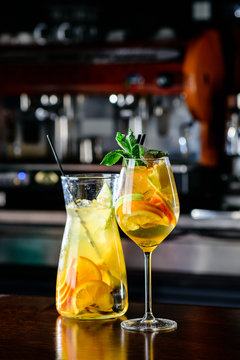 Closeup glass of white sparkling wine sangria decorated with citrus slices at bright bar counter background.