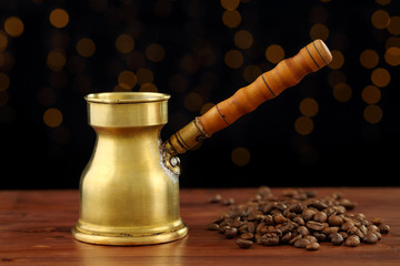 Beautiful and shiny vintage brass turkish coffee pot with carved handle on a dark wooden table with...