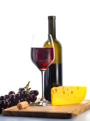 A glass with red wine, cheese, grapes and a bottle of wine on a light background. Light drink and snack