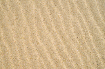 Fototapeta na wymiar Yellow sand with waves on beach closeup