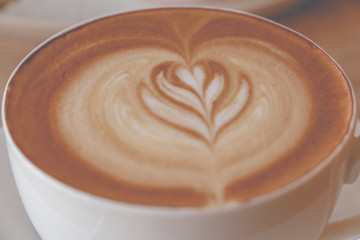 Close up Cup of coffee latte art in coffee shop vintage color tone.