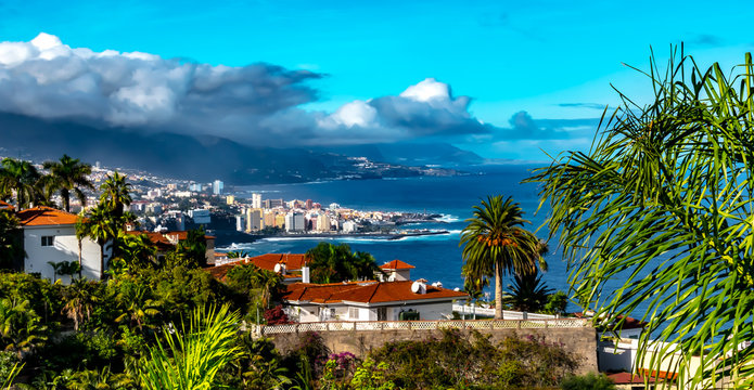Tenerife - Puerto de la Cruz is the tourist center of the island north coast on Tenerife. A view along the coast to the harbor town, on a sunny day with clouds gathering in October.