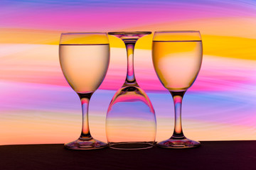 Three wine glasses in a row with colorful light painting behind