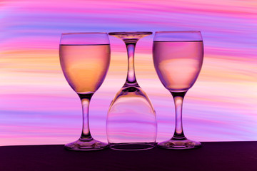 Three wine glasses in a row with colorful light painting behind