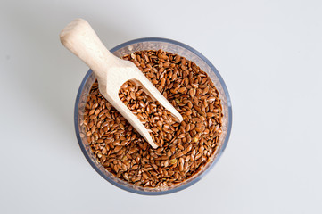 Top view, flat lay. A jar filled with brown flax seeds. White background. Close up, macro.