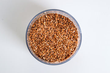 Top view. A jar filled with brown flax seeds. White background. Close up, macro.