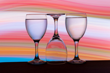 Three wine glasses in a row with colorful light painting behind