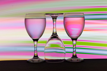 Three wine glasses in a row with colorful light painting behind