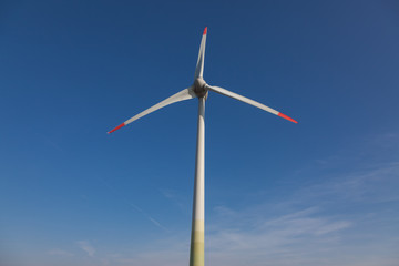 wind turbine with sun flare blue sky background view from below