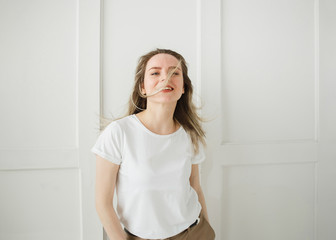 Emotional Portrait of Beautiful Active Caucasian Woman Indoor at White Wall, Looking at Camera, Smiling, Flying Hair - Happiness, Carefree, Healthy Lifestyle concept.