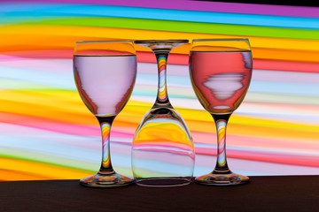 Three wine glasses in a row with colorful light painting behind