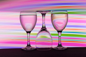 Three wine glasses in a row with colorful light painting behind