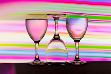 Three wine glasses in a row with colorful light painting behind