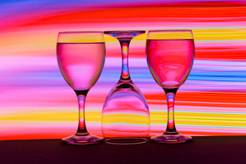 Three wine glasses in a row with colorful light painting behind