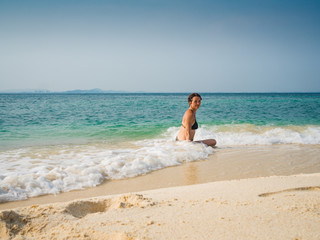 Fototapeta na wymiar Portrait of happy woman in bikini sitting in sea water