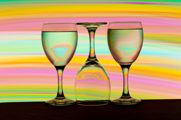 Three wine glasses in a row with colorful light painting behind