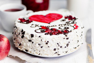 delicious cake with a red heart and pattern on a light background