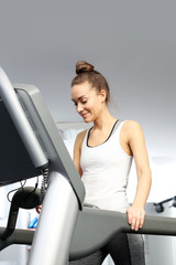 Walking on a treadmill. A young woman in an exercise room is running on an automatic treadmill.