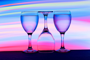 Three wine glasses in a row with colorful light painting behind