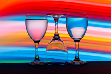 Three wine glasses in a row with colorful light painting behind